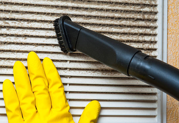 hand in yellow glove and vacuum cleaner pipe. ventilation grill cleaning. hand in yellow glove and vacuum cleaner pipe. ventilation grill cleaning.